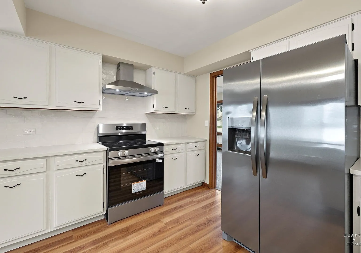 Kitchen with white cabinets, stainless range and hood after refresh, Huntley IL case study